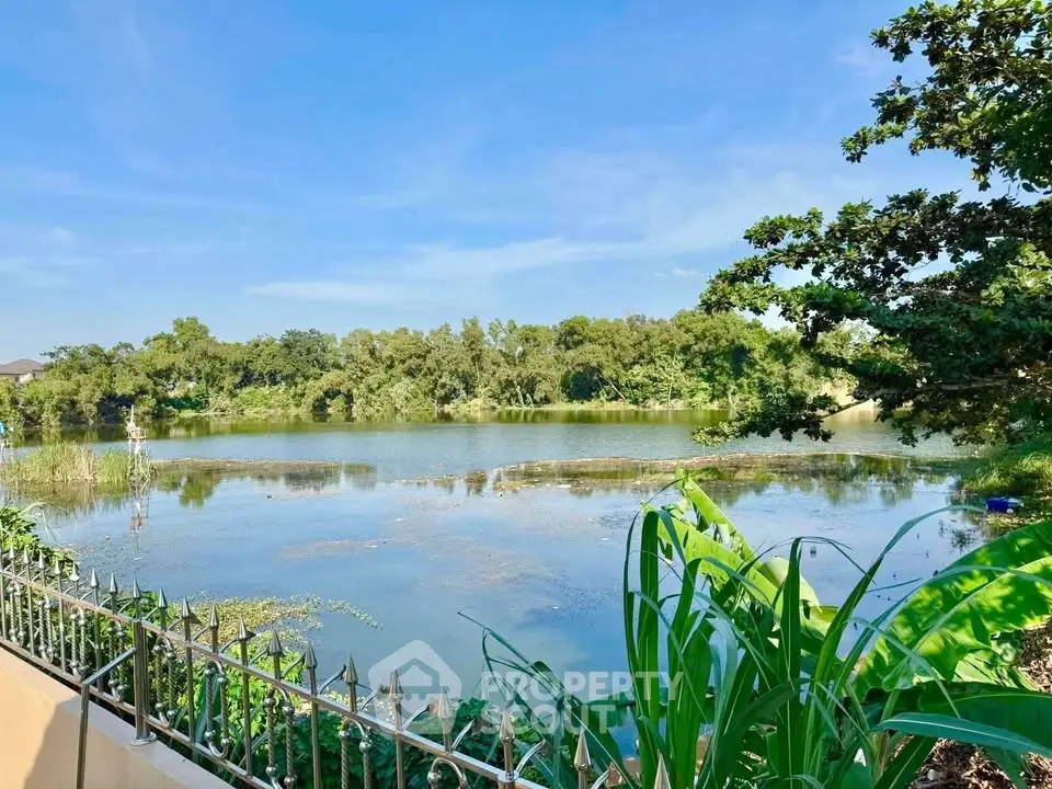 Stunning lakeside view with lush greenery and clear blue sky, perfect for serene living.