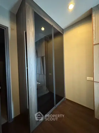 Modern storage space with sleek wooden wardrobe and dark glass doors