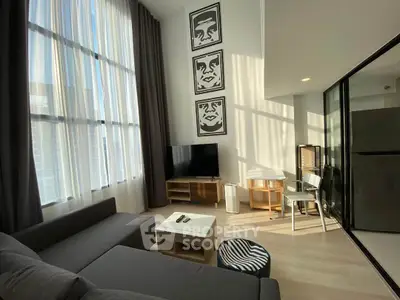Modern living room with high ceilings, large windows, and stylish decor in a bright apartment.