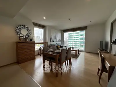 Spacious modern living room with dining area and city view, featuring elegant decor and natural light.