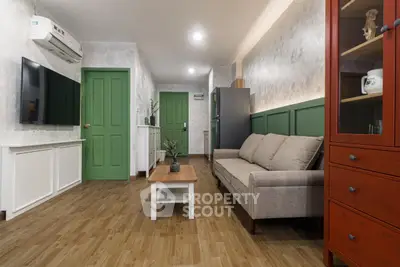 Charming living room with modern decor, green accents, and cozy seating in a stylish apartment.