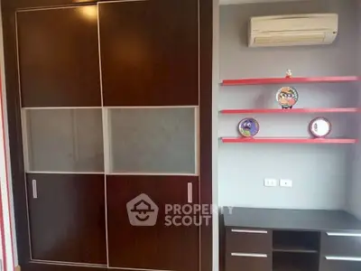 Modern bedroom with sleek wardrobe and air conditioning unit, featuring stylish red shelves and desk.