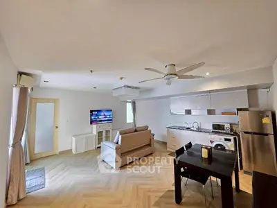 Spacious open-plan living room with modern kitchen and dining area, featuring sleek appliances and cozy seating.