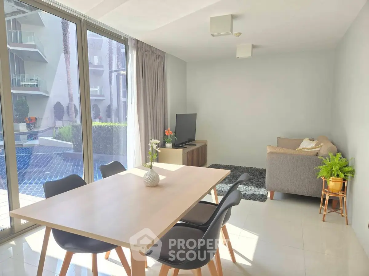 Modern living room with pool view, stylish furniture, and abundant natural light.
