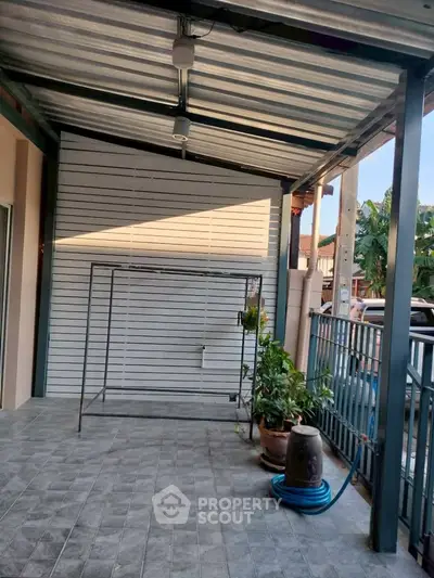 Spacious covered patio with tiled flooring and garden view, perfect for outdoor relaxation.