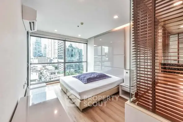 Modern bedroom with city view, large windows, and stylish decor in urban apartment.