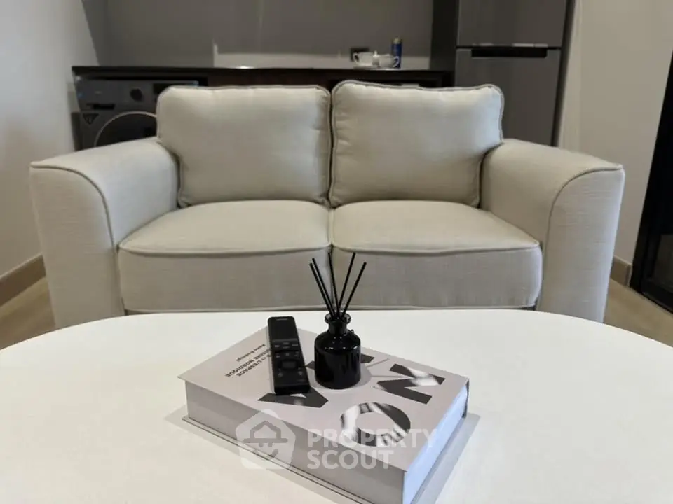 Modern living room with cozy sofa and stylish decor, featuring a sleek kitchen in the background.