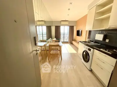 Modern apartment interior with open kitchen and living area, featuring washing machine and stylish decor.