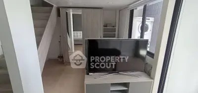 Modern living room with sleek TV setup and mirrored wardrobe in stylish apartment.