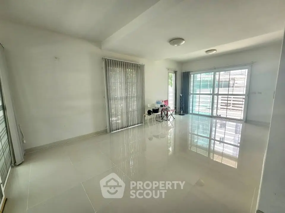 Spacious and bright living room with large windows and glossy tiled floors.
