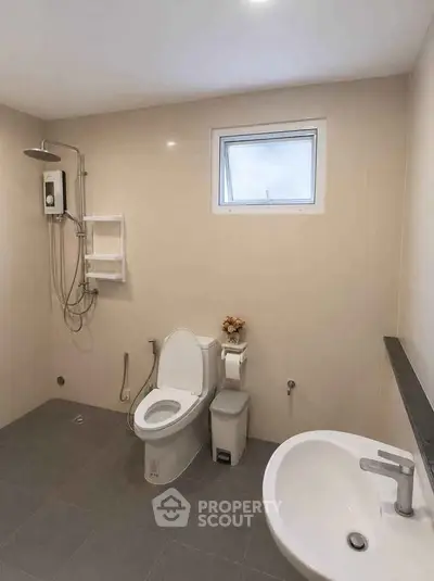 Modern bathroom with sleek fixtures and neutral tones, featuring a shower and toilet.