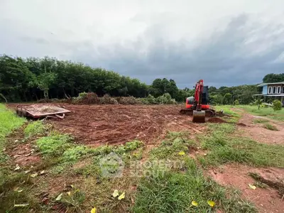 Expansive land plot with lush greenery and construction equipment, ideal for development opportunities.