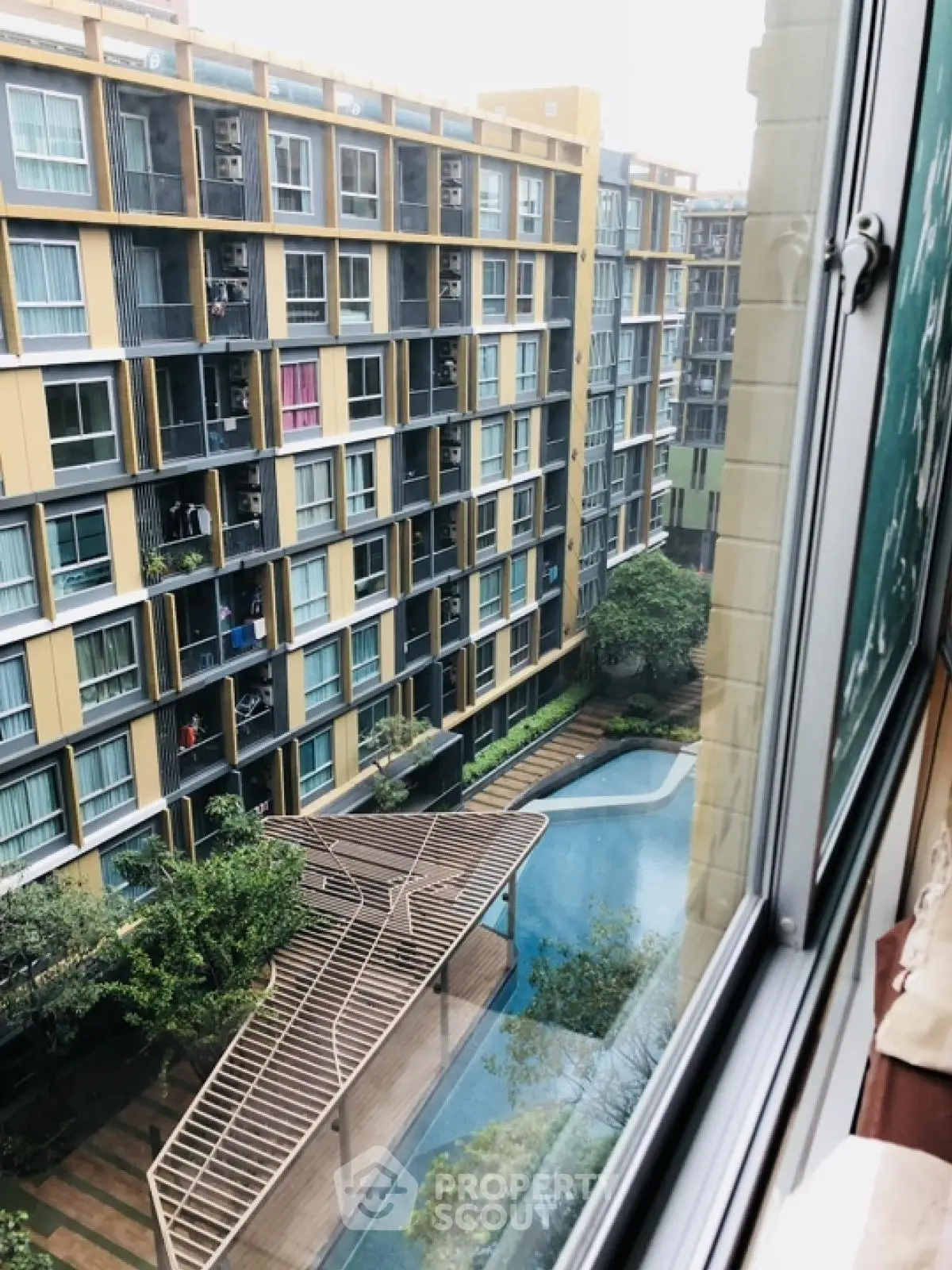 Modern apartment complex with pool view from window, showcasing urban living.