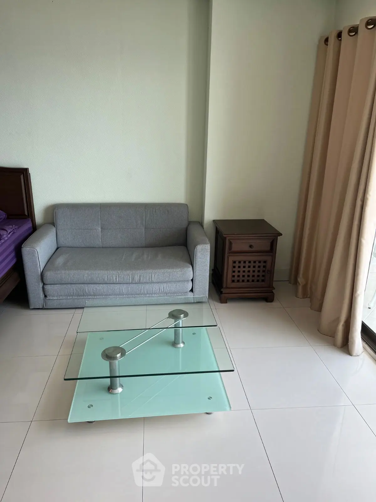 Cozy living room with modern glass coffee table and gray sofa, ideal for relaxation.