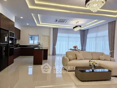 Luxurious open-plan living room and kitchen with elegant chandeliers and modern furnishings.