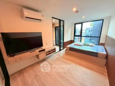 Modern bedroom with large window and wall-mounted TV in a stylish apartment.