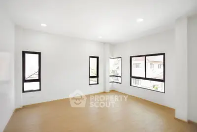 Spacious and bright empty room with large windows and wooden flooring, perfect for customization.