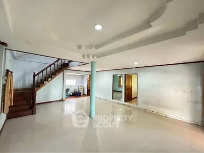 Spacious open-plan living area with staircase and unique ceiling design in a modern home.