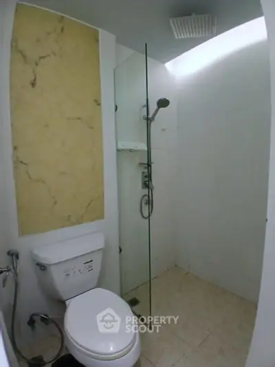 Compact modern bathroom with glass shower and marble accent wall