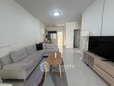 Spacious living room with modern furniture and open kitchen layout, perfect for comfortable living.