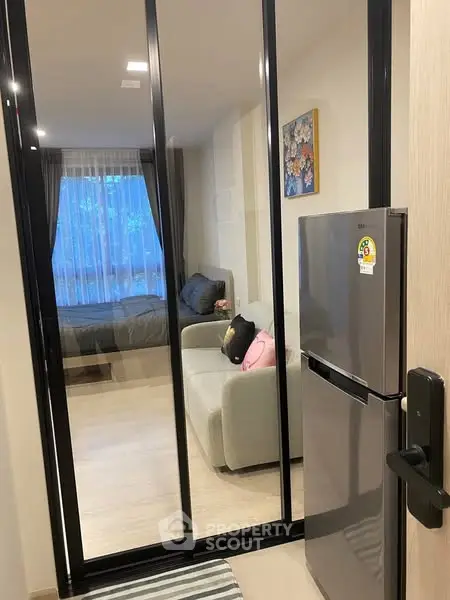 Modern apartment with glass partition, cozy living area, and sleek kitchen appliances.