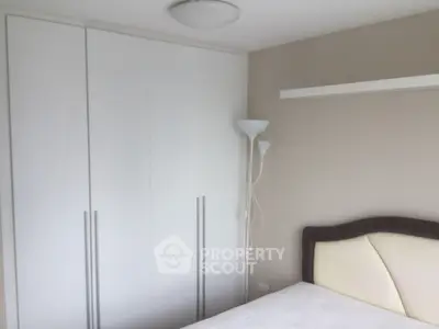 Modern bedroom with sleek white wardrobe and elegant headboard design.