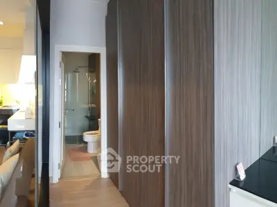 Modern apartment hallway with sleek wooden cabinets and view into a stylish bathroom.