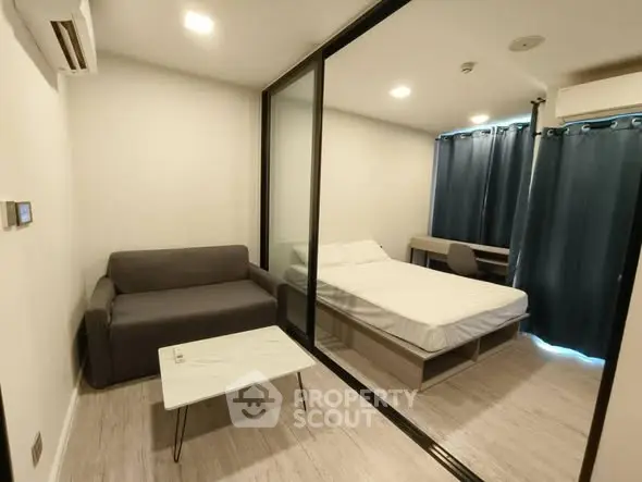 Modern studio apartment with glass partition, cozy sofa, and minimalist decor.