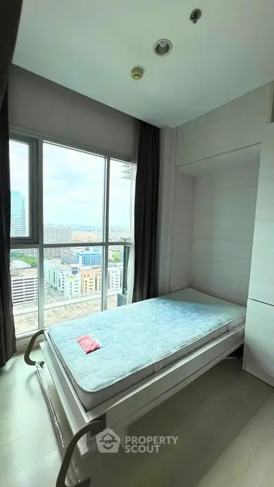 Bright bedroom with city view, featuring a single bed and large window for natural light.