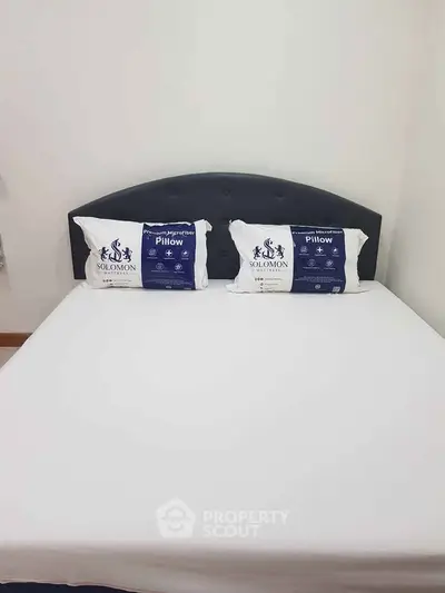 Cozy bedroom with a neatly made bed and stylish headboard, perfect for restful nights.