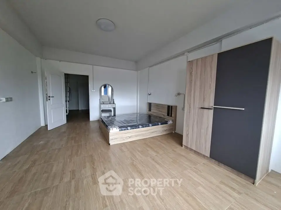 Spacious bedroom with modern wooden flooring and stylish wardrobe