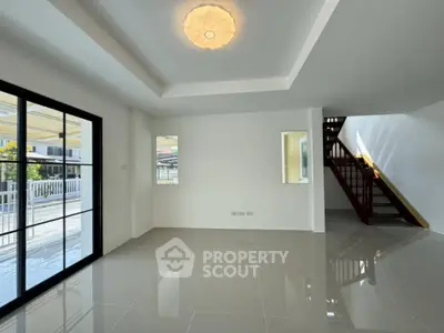 Spacious modern living room with glossy tile flooring and elegant staircase