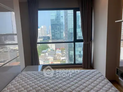 Modern bedroom with city view from large window in high-rise apartment.