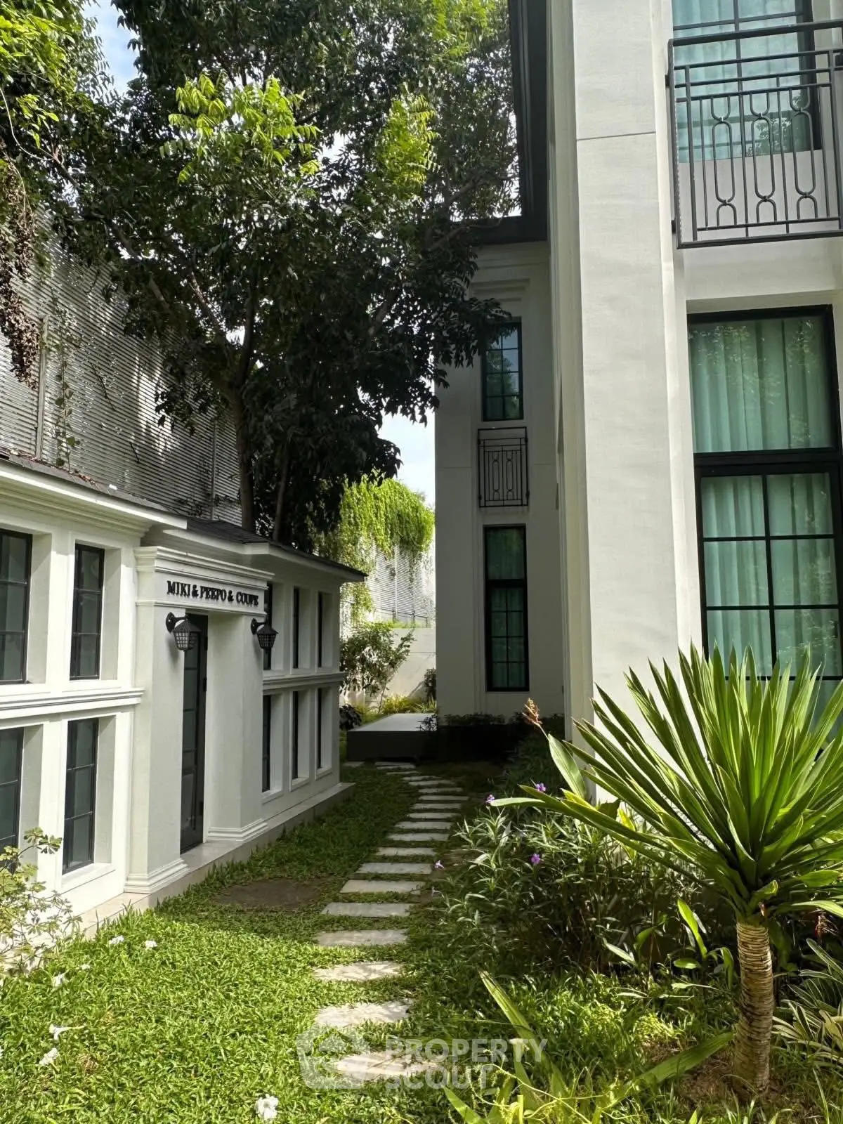 Charming garden pathway between modern buildings with lush greenery