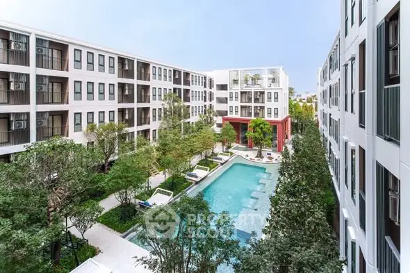 Modern apartment complex with central pool and lush greenery