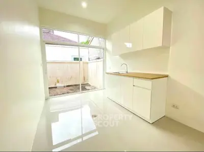 Bright and modern kitchen with sleek white cabinetry and large window view.