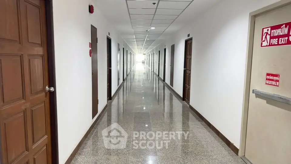 Spacious and well-lit apartment hallway with polished floors and multiple doors.