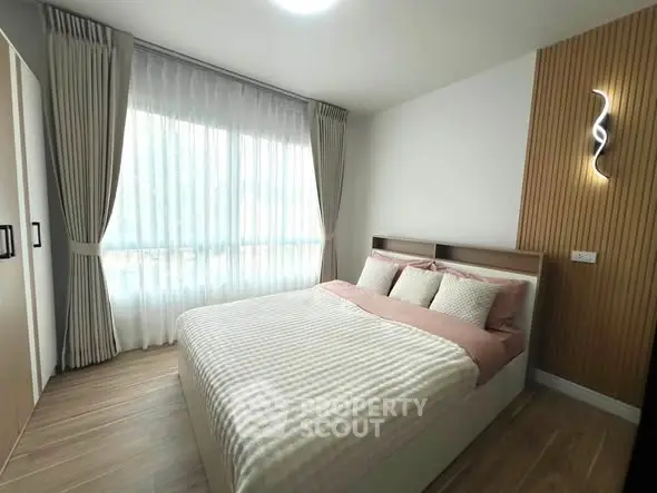 Modern bedroom with large window and stylish decor in a cozy apartment.
