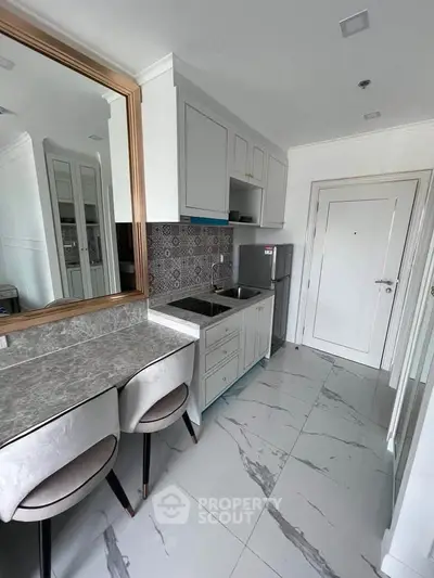 Modern kitchen with sleek design, marble flooring, and compact dining area in a stylish apartment.