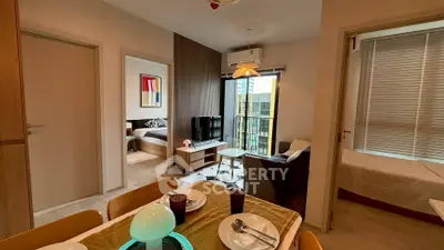 Modern apartment interior with open living room, dining area, and bedroom view.