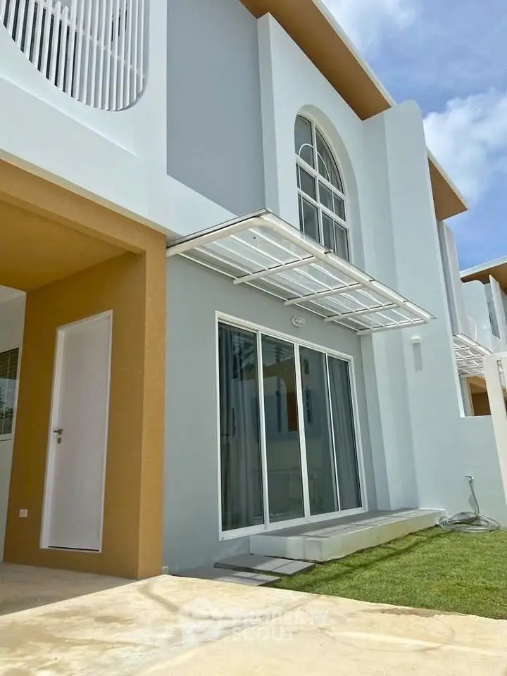 Modern two-story house with large windows and sleek architectural design.
