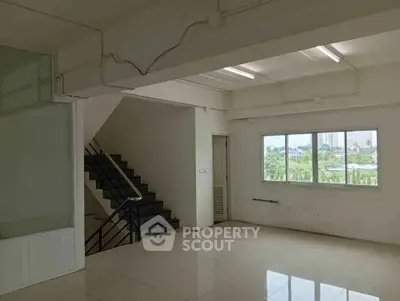 Spacious interior with staircase and large window offering natural light and city views.