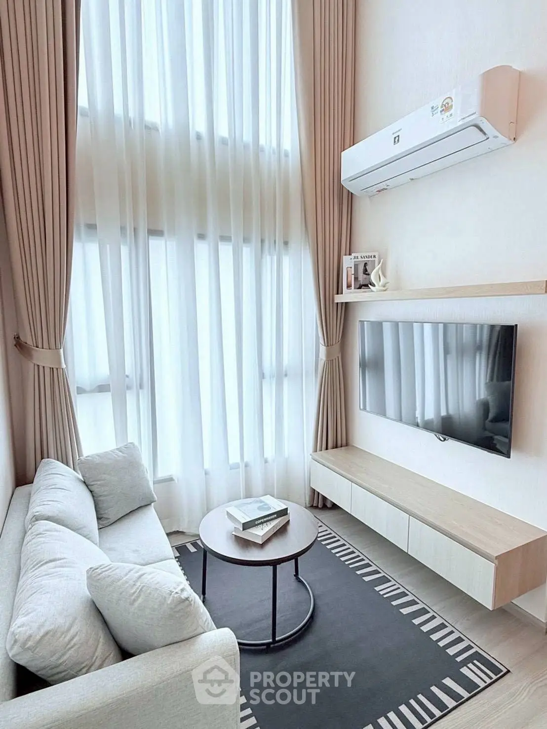Modern living room with high ceilings, elegant curtains, and wall-mounted TV