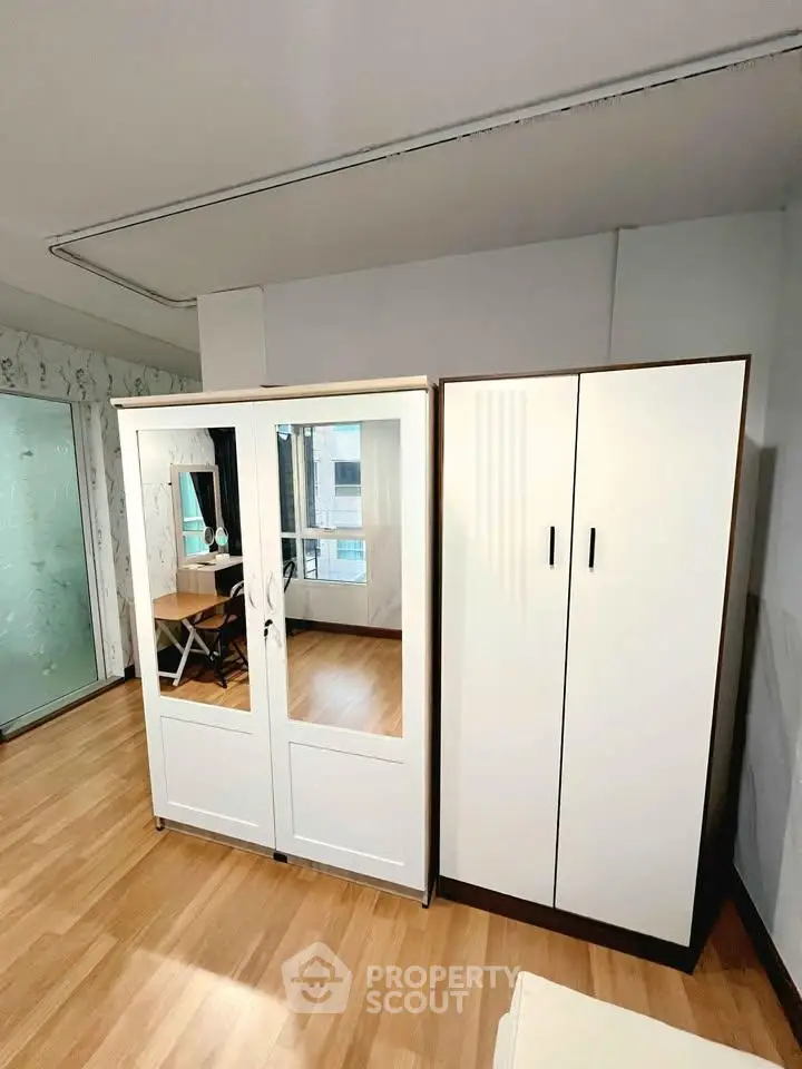 Spacious bedroom with modern wardrobe and wooden flooring, perfect for urban living.