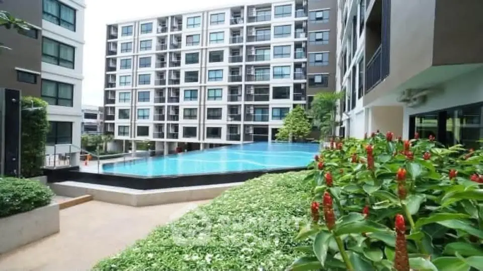 Modern apartment complex with a stunning pool and lush greenery, offering a luxurious lifestyle.