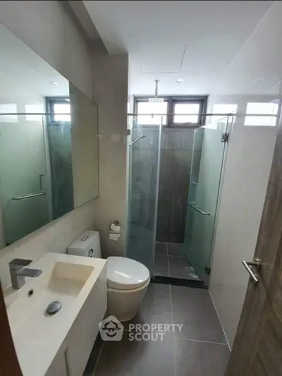 Modern bathroom with glass shower and sleek fixtures in contemporary apartment.