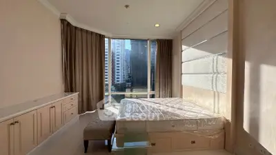 Spacious bedroom with large windows offering city views and elegant decor.