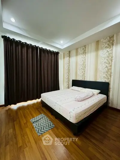 Spacious bedroom with elegant wooden flooring and stylish wallpaper, featuring a comfortable bed and large window curtains.