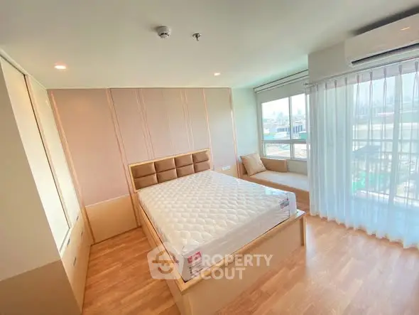 Spacious bedroom with large window and modern decor in a bright apartment.