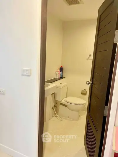 Compact bathroom with modern fixtures and wooden door, ideal for efficient space utilization.
